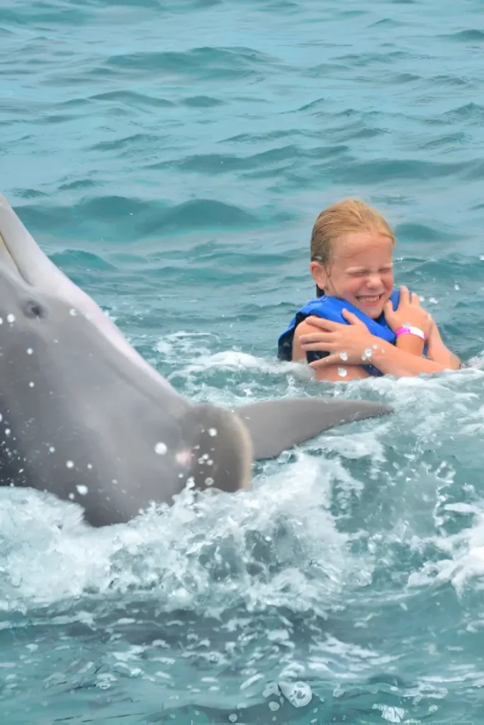 child swimming with dolphin happily