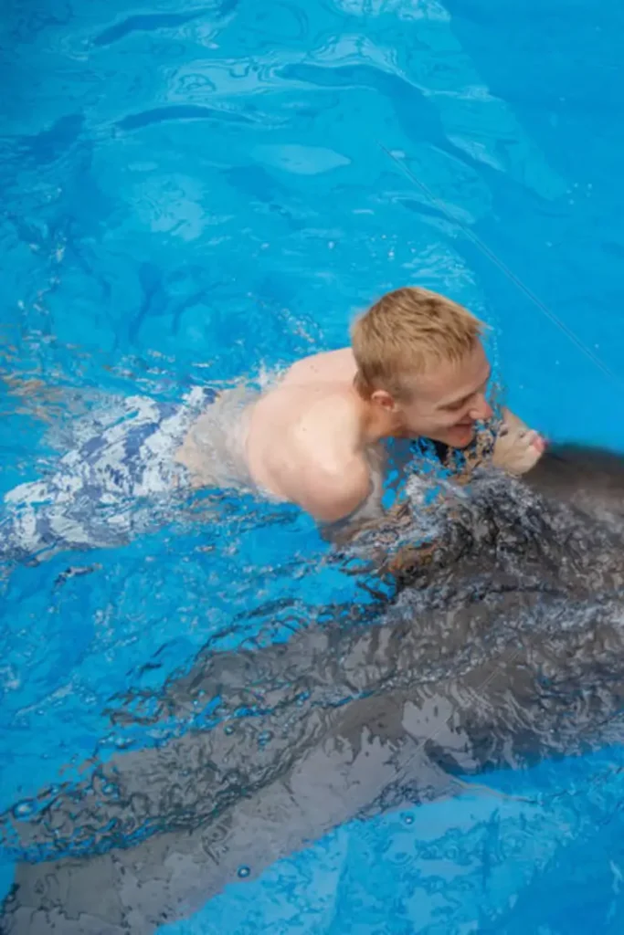 man swimming with dolphin in the pool