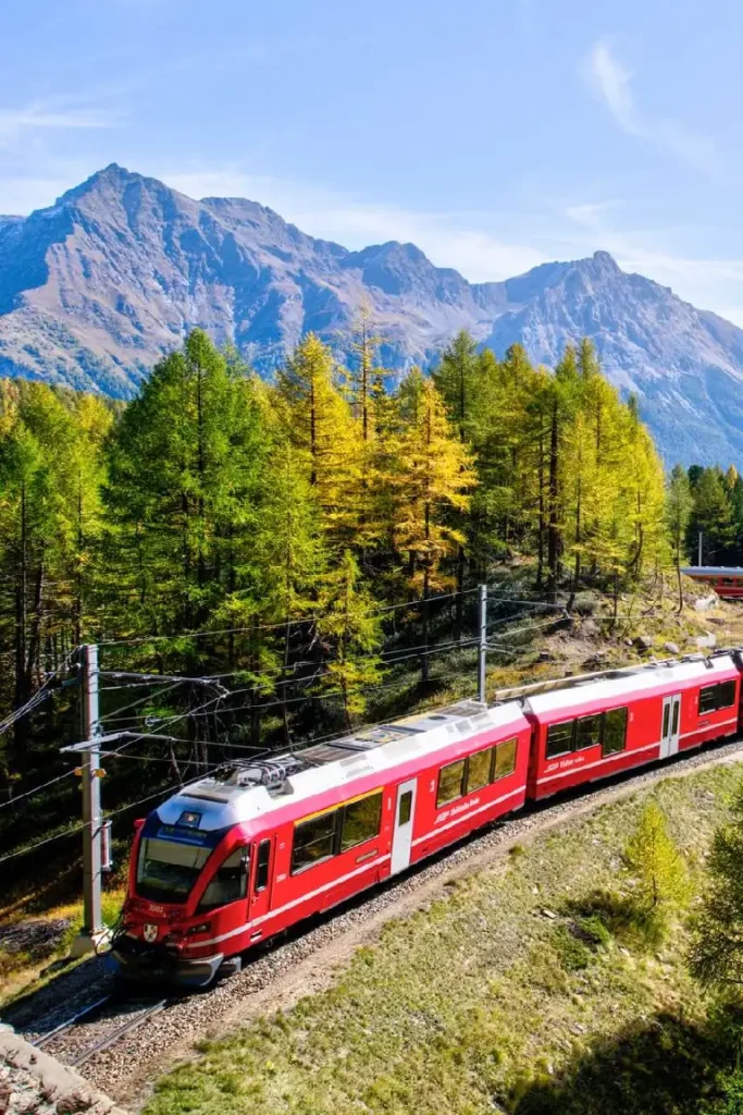 red train running on trails in switzerland