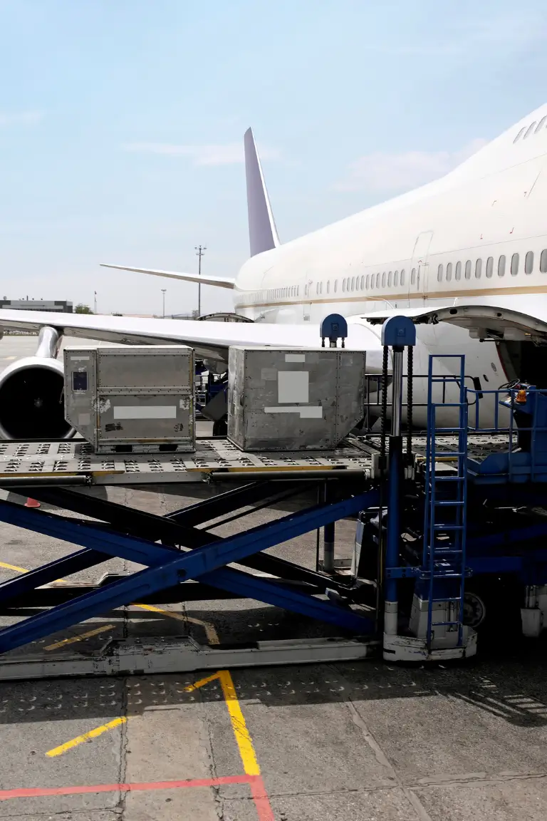 large white commercial airplane being loaded with cargo containers at an airport