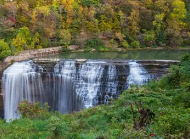 a breathtaking view of Lower Falls waterfall in Rochester, New York, surrounded by vibrant autumn foliage reflecting the changing seasons