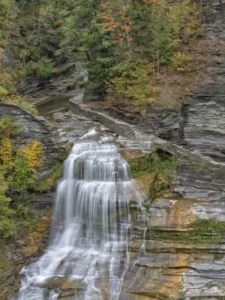 breathtaking view of Lucifer Falls, a majestic waterfall cascading over layered rocks surrounded by the vibrant autumn foliage in Rochester, Upstate New York