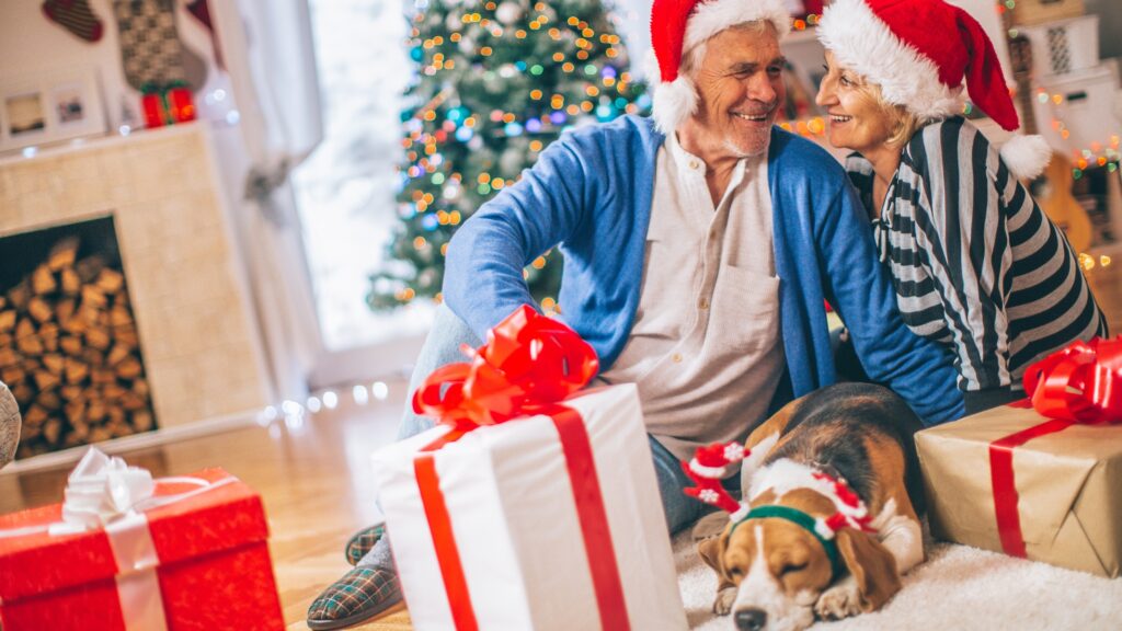 a man and woman sitting on the floor with a dog and a present